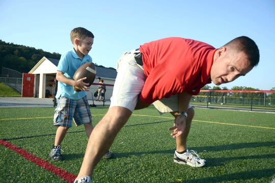 Announcer Kevin Lawrence hikes the ball to his son, 6-year-old Connor Lawrence before the football game at Susquehannock High School Friday, August 31, 2012.