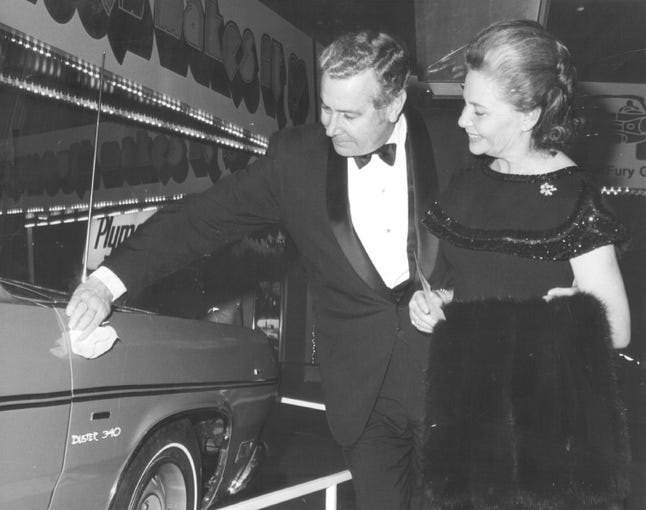 Chrysler President Lynn Townsend dusts off a Plymouth Duster while his wife Ruth watches at a black-tie event on November 14. 1969.
