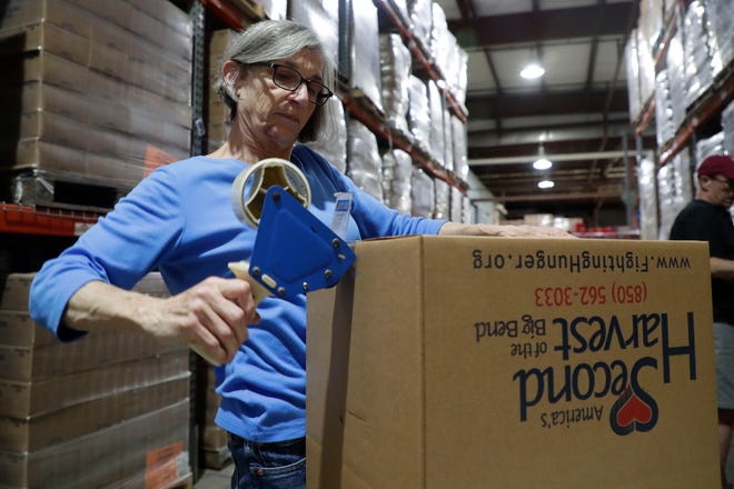 Chris Franzetti tapes together boxes as she volunteers with many others at Second Harvest Food Bank. The volunteers work as a team to package nonperishable food items to send to the Carolinas following the destruction from Hurricane Dorian.