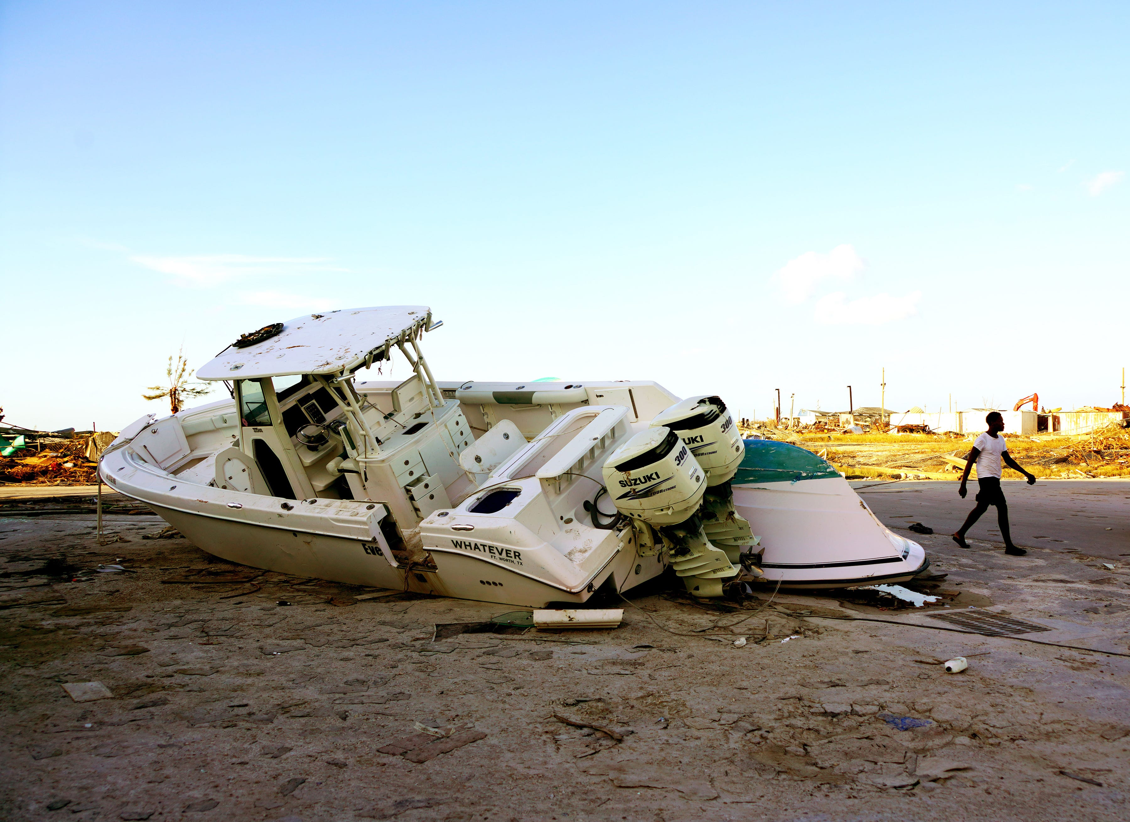 A Hurricane Dorian survivor walks past a beached powerboat in Marsh Harbour, Abaco Island, in the Bahamas on Sept. 5, 2019.