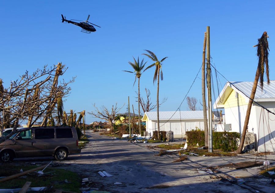 A helicopter flies over homes damaged by Hurricane Dorian on Treasure Cay in The Bahamas on Sept. 7, 2019. 
