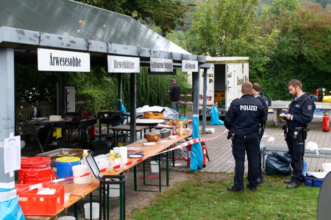 In this Sunday, Sept. 8, 2019 photo police officers investigate a booth after an explosion at a village festival in Freudenberg, Germany.