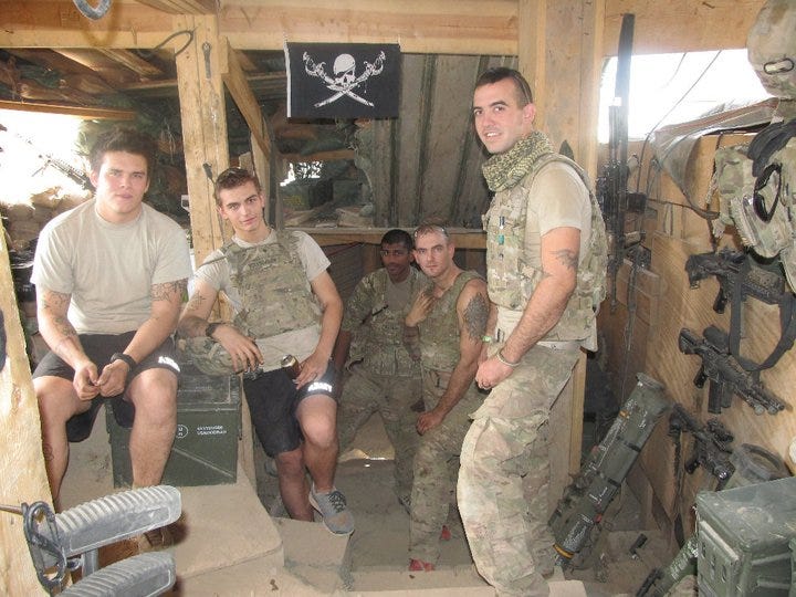 Tope (at right) poses with fellow soldiers in Kunar Province, Afghanistan, in November 2011. His superiors made the group take down the pirate flag, Tope says.