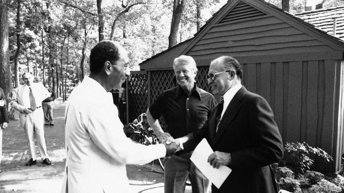 ORG XMIT: APHS359015 In this Official White House photo, Egyptian President Anwar Sadat, left, shakes hands with Israeli Prime Minister Menachem Begin as President Jimmy Carter looks on outside a lodge at Camp David, Maryland on Sept. 7, 1978. (AP Photo/Official White House Photo) NO SALES [Via MerlinFTP Drop]