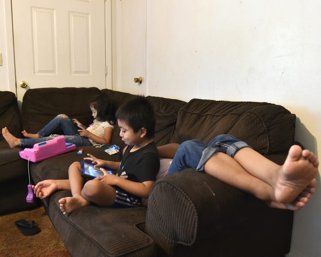 Siblings play games on their couch in the living room of their Carthage, Mississippi home on Wednesday, Sept. 4, 2019 as their exhausted mother rests after being released from immigration detention on a $3,000 bond. While she was locked up for three weeks, her husband E. Miranda had to stop working to take care of their three children.