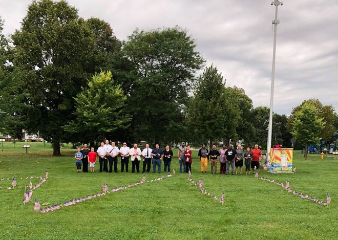 During the 9/11 Never Forget Ceremony, community members placed flags in the ground of the date 9/11 as well as took part in a three-minute moment of silence in remembrance. Pictured are from left: Aaron Bell, Heather Bell, Austin Bell, Fond du Lac Fire Rescue Assistant Chief Troy Haase, Assistant Chief Erick Gerritson, Assistant Chief Todd Janquart, Assistant Chief James Knowles, City Council Member and event organizer Ben Giles, Fond du Lac Fire/Rescue Chief Peter O’Leary, City Council Member Dan Degner, Lisa Chambers Siefert  James Graves, Ellen Wendlandt, Shavana Talbert, Vicente Lezama, Daisy Frazier, Antonio Godfrey, Loree Shady and Zoe Leu. Others who attended included event organizer Bre Zoch, JJ Raflik, Representative Jeremy Thiesfeldt and Father Ryan Pruess.