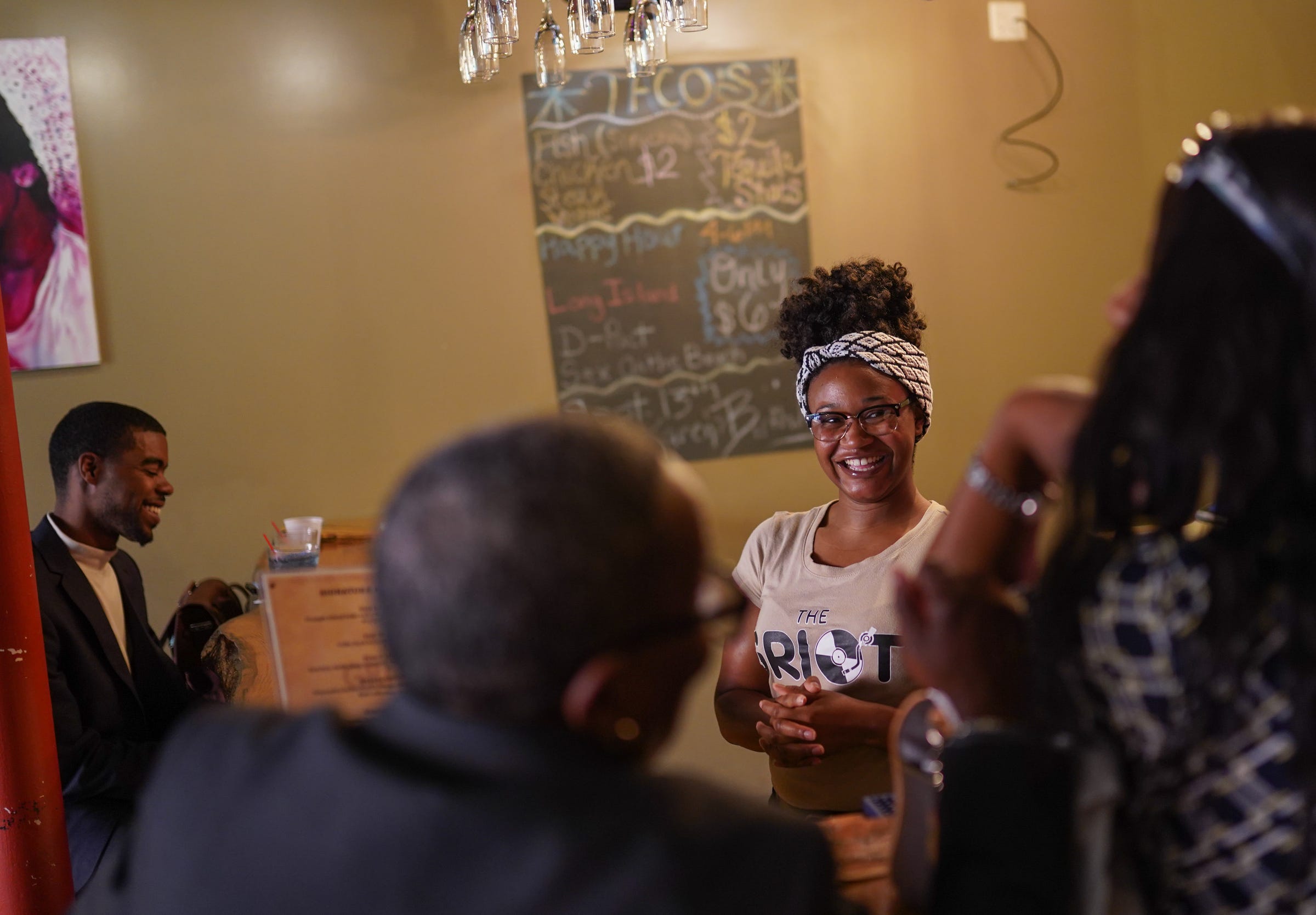 Wayne State University student DeLawren Bradshaw, who is working two part-time jobs to limit her student loan debt, talks with customers while bartending at Griot Music Lounge in Detroit on Tuesday, September 10, 2019.