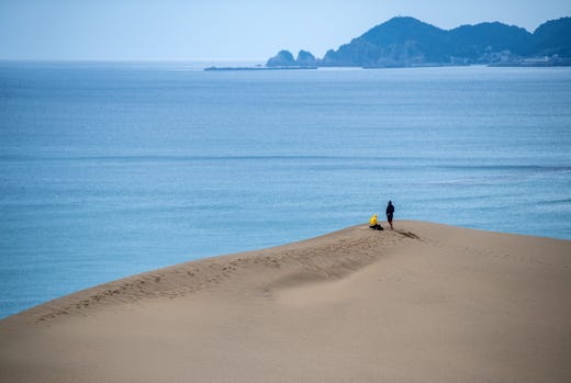 People visit Tottori Sand Dunes on Aug. 27, 2019 in Tottori, Japan. The Tottori Sand Dunes form the only large dune system in Japan and were created by sediment deposits carried by the Sendai River into the Sea of Japan. Sea currents and wind brought the sand from the sea floor to the shore, where the wind constantly rearranges the shape. The dunes have existed for over 100,000 years but are now decreasing due to a post-war government reforestation program and concrete barriers erected to protect the coast from tsunamis which have disrupted the currents responsible for bringing the sand to shore.