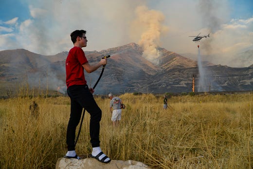 Caden Terry, 15, does what he can as he joins neighbors in cutting down tall brush as crews battle a grass fire in Tooele, Utah being dubbed the Green Ravine fire as it burns on Sept. 3, 2019.