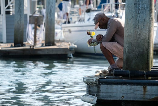 James Miranda, right, of Santa Barbara, holds flowers and takes a moment to reflect at a dock near the Sea Landing at Santa Barbara Harbor in Santa Barbara, Calif., Sept. 2, 2019. A fire raged through a boat carrying recreational scuba divers anchored near an island off the Southern California coast early Monday, leaving multiple people dead and hope diminishing that any of the more than two dozen people still missing would be found alive.
