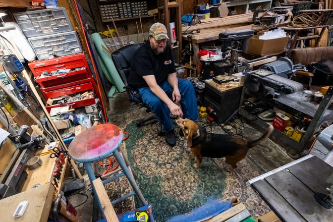 Mike Britz reaches down for his 10-year-old Beagle Boom Boom in his St. Clair workshop Friday, Sept. 13, 2019. Britz says Boom Boom is the CEO of his woodworking shop.