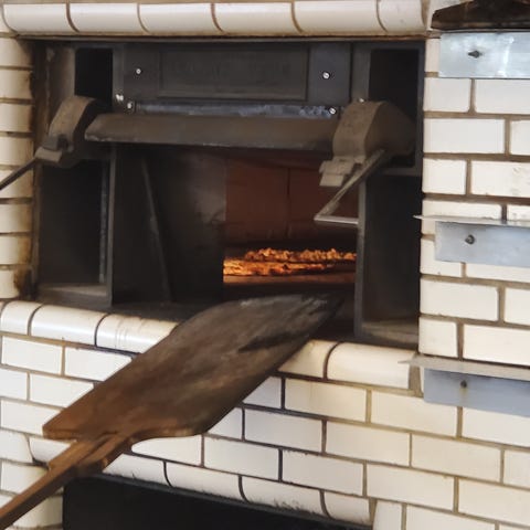 Pizzas cook inside the coal-burning oven, the same