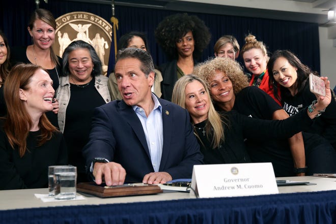 Surrounded by supporters and activists, New York Gov. Andrew Cuomo signs a bill that increases the statute of limitations in rape cases during a bill signing ceremony in New York, Wednesday, Sept. 18, 2019. Actresses Julianne Moore, left, Mira Sorvino, fourth from right, and Michele Hurd, third from right, were there as supporters of the bill and as members of the Time's Up movement, which advocates for women's rights. (AP Photo/Seth Wenig)