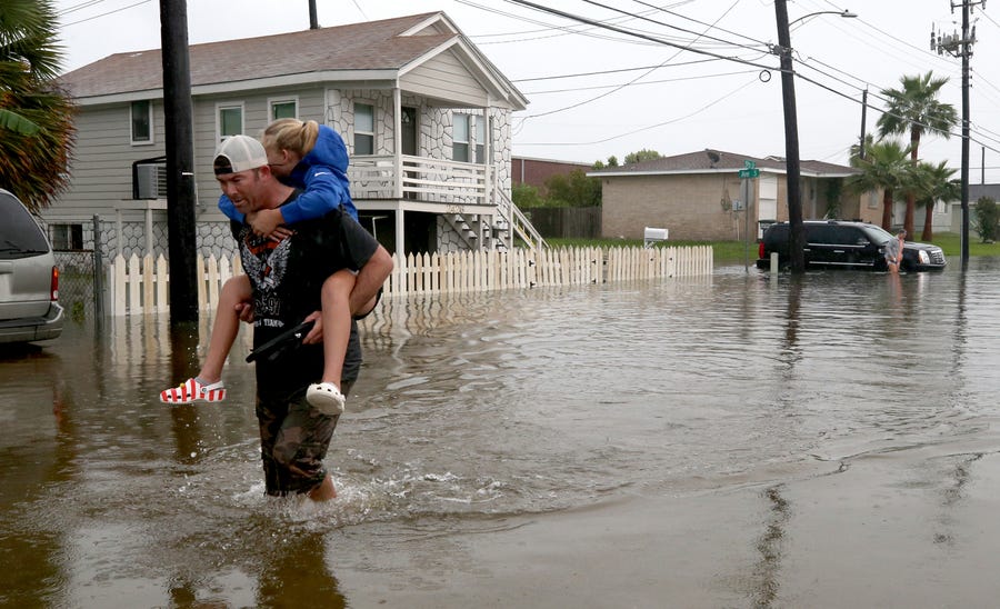Terry Spencer carries his daughter, Trinity, through high water in Galveston, Texas, on Sept. 18, 2019, as heavy rain from Tropical Depression Imelda caused street flooding on the island.