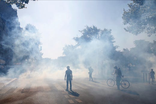 Protestors stand in a smoke of teargas during a climate demonstration, in Paris, Saturday, Sept. 21, 2019. Scuffles broke out in Paris between some violent activists and police which responded with tear gas at a march for climate gathering thousands of people in Paris.
