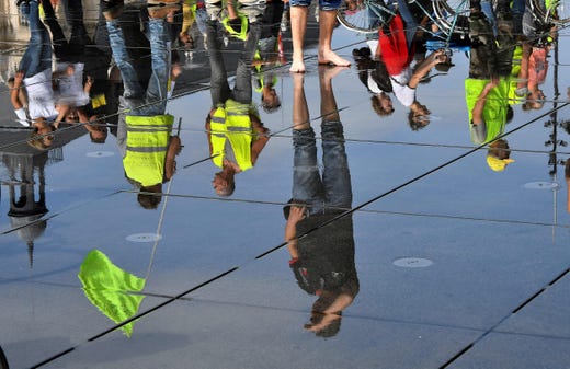 Protestors are reflected in water on a pavement as they march during a climate change and 'yellow vest' protest in Bordeaux, south-west France on Sept. 21, 2019, during which a crowd of between 2,000-3,000 marched along the banks of the River Garonne.