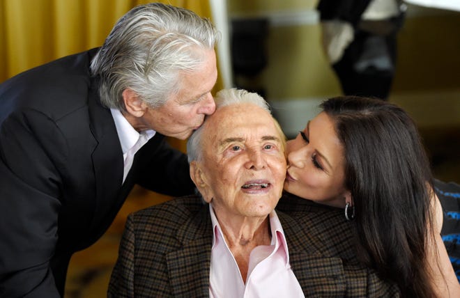 Actor Kirk Douglas, center, gets a kiss from his son Michael Douglas, left, and Michael's wife Catherine Zeta-Jones during his 100th birthday party at the Beverly Hills Hotel on Friday, Dec. 9. 2016, in Beverly Hills, Calif.