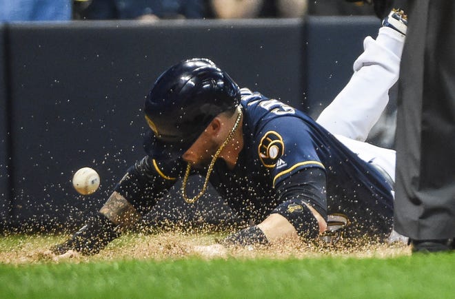Brewers catcher Yasmani Grandal scores a run in the sixth inning Saturday night at Miller Park.