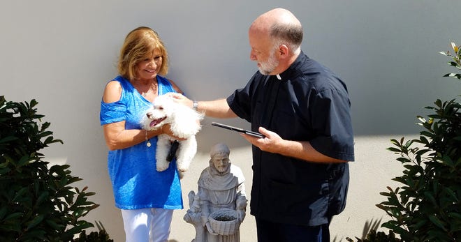 Suntree resident June Mikell holds furry best friend Lucas as Pastor David Jahn of Advent Lutheran Church blesses the pup. Advent will host its annual Blessing of the Animals both in Suntree and Melbourne on Saturday, Oct. 5. Photo---