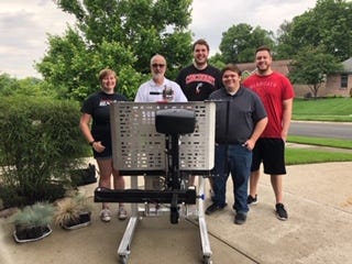 University of Cincinnati QL+ students pose with Vietnam veteran Mike Donnelly in front of a scooter rack lift device they designed.