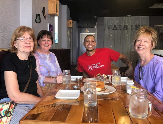 Village Food Tours founder Halim Urban, in red, and guests enjoy a tour stop at Paisley Vegan Kitchen in Cocoa Village.
