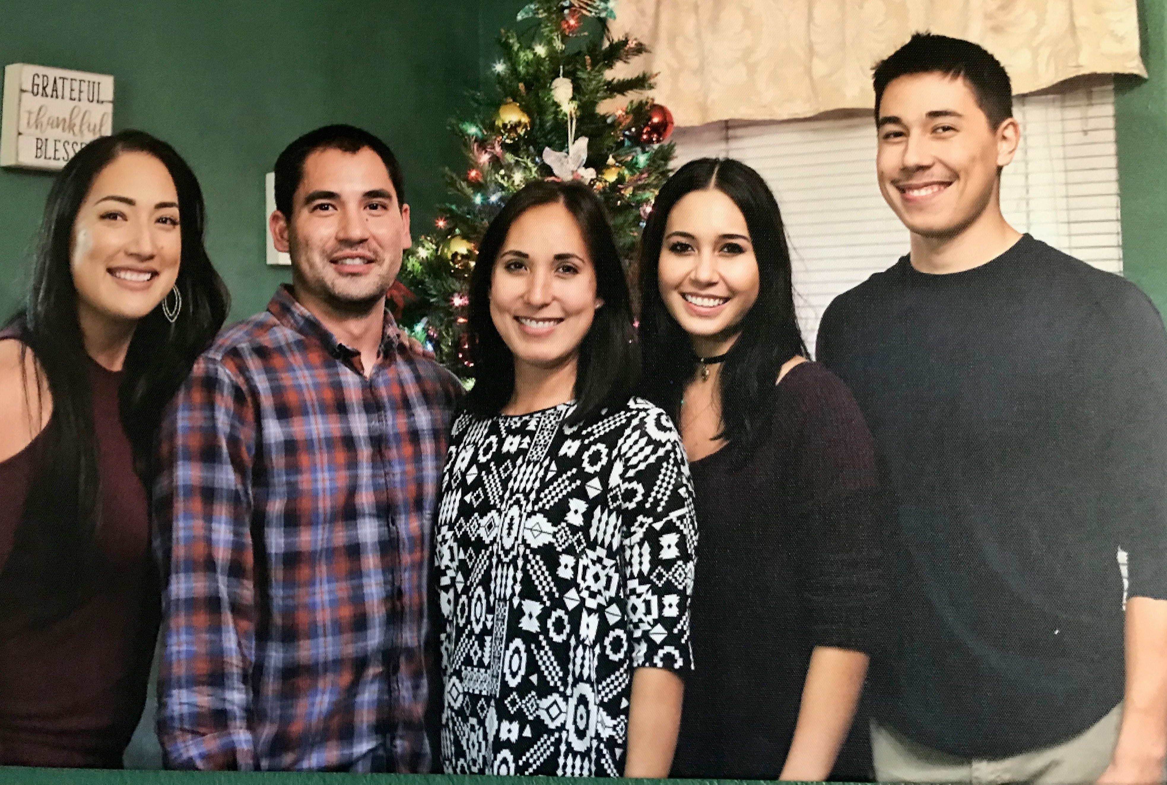 John David Adena, wearing a flannel shirt, poses with his siblings for a Christmas picture.
