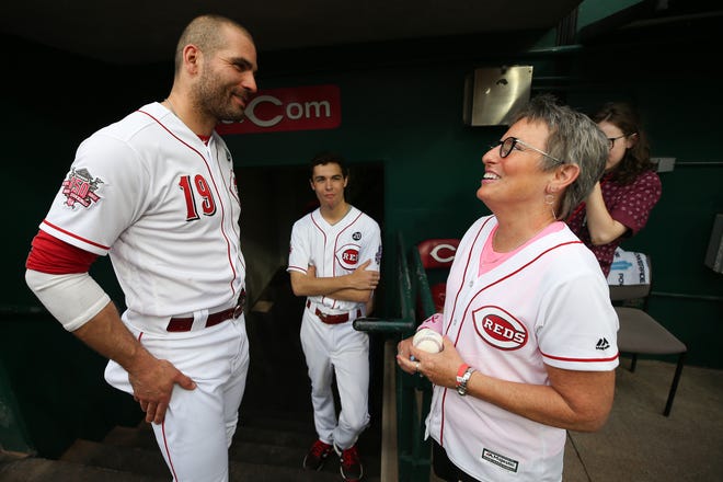 Cancer survivor Laura Fay, who served as the team's honorary bat girl, receives an autograph from Cincinnati Reds first baseman Joey Votto (19) before the first inning of an MLB baseball game against the Chicago Cubs, Thursday, May 16, 2019, at Great American Ball Park in Cincinnati. 