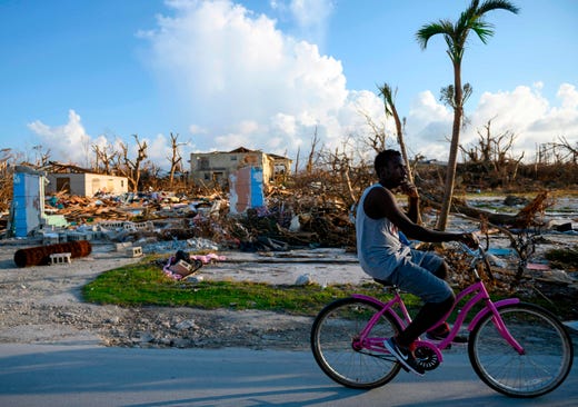 A man bikes past destroyed homes in Marsh Harbour, Bahamas on Sept. 10, 2019, one week after Hurricane Dorian. Bahamas authorities have updated the death toll from Hurricane Dorian to 50 with the number expected to climb, local media reported, as thousands are evacuated from the archipelago's hardest-hit islands.