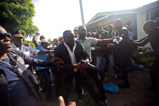 Ruling party Senator Willot Joseph holds a gun as he arrives for a vote on the ratification of Fritz William Michel's nomination as prime minister in Port-au-Prince, Haiti, Sept. 23, 2019. Opposition members confronted ruling-party senators, and Joseph pulled a pistol when protesters rushed at him and members of his entourage. The vote was cancelled.