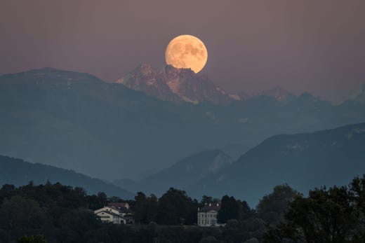 A near full moon rises behind The French Alps as seen from Geneva on Sept. 12, 2019.