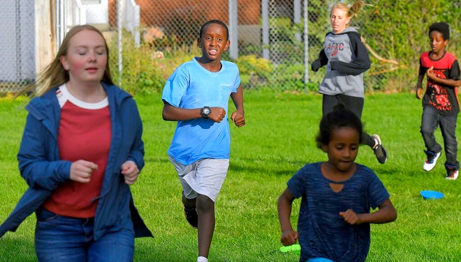 In this Sept. 11, 2019, photo Salman Yusuf, second from left, and others run laps on the field at Ellis Elementary School in Logan, Utah. Yusuf, who is a refugee from Somalia, is one of many kids who participate in the after school running club. (Eli Lucero/The Herald Journal via AP)