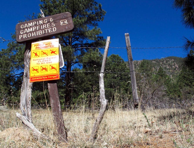 FILE - In a Thursday, May 24, 2018, file photo, a sign posted at a trail leads into the national forest in Flagstaff, Ariz.  Monsoon season carries high hopes for rain, thunder and lightning across the US Southwest, but it failed to deliver this year. Several communities in northern Arizona had the driest monsoon season on record, including Flagstaff. The season is characterized by a shift in wind patterns and moisture being pulled in from the tropical coast of Mexico. It runs from mid-June through September. (AP Photo/Felicia Fonseca, File)