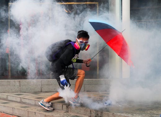 An anti-government protester holding an umbrella holds a tear gas canister before throwing it towards police officers during a Global Anti Totalitarianism Rally in Hong Kong, China, Sept. 29 2019. Hong Kong has entered its fourth month of mass protests, originally triggered by a now suspended extradition bill to mainland China, that have turned into a wider pro-democracy movement.