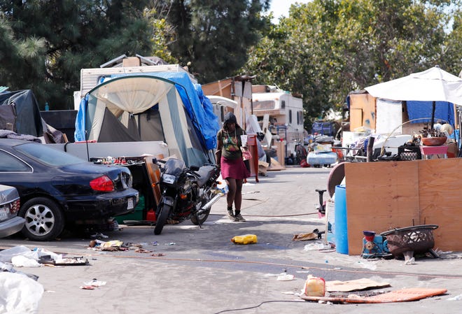 A woman walks through a homeless encampment where Julian Castro, San Antonio mayor, presidential candidate and former Secretary of Housing and Urban Development visited in Oakland, Calif., on Sept. 25, 2019.