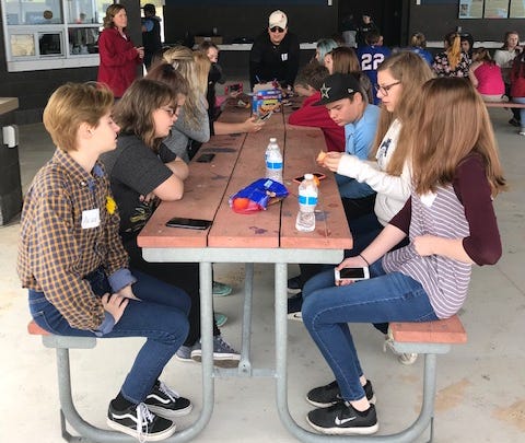 Hannah Rodriguez stands at the end of a table full of Manistee Commitment Scholars during a Community Service Day during last school year