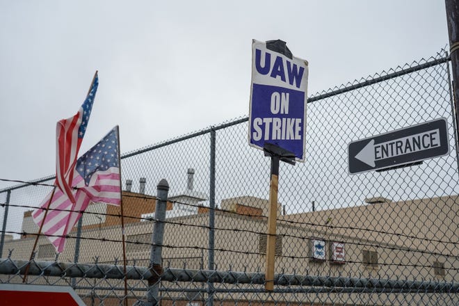 American flags and UAW strike signs sit attached to a fence outside of General Motors Flint Assembly as workers remain on strike with General Motors over contract negotiations on Wednesday, October 2, 2019.