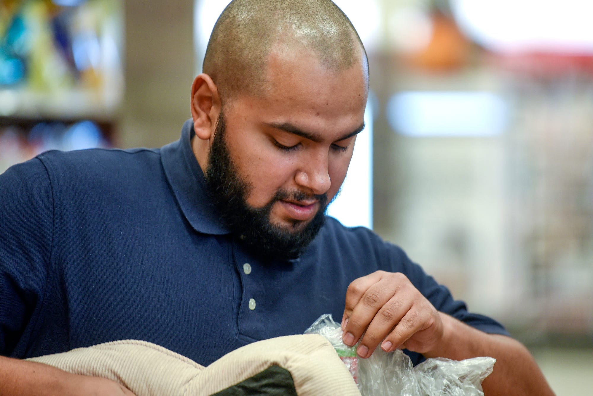 Benito Flores, 25, works on unpacking boxes for another employee while working a shift on Thursday, Oct. 3, 2019, at the Rite Aid in East Lansing. Flores is working two jobs to help out with his $10,000 in student debt.