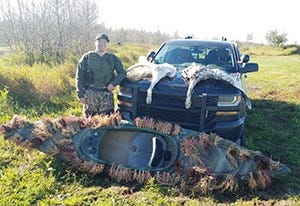 Conservation Officer Cody Smith is pictured with two trumpeter swans poached on Sept. 28, the opening day of waterfowl hunting season in the Upper Peninsula.