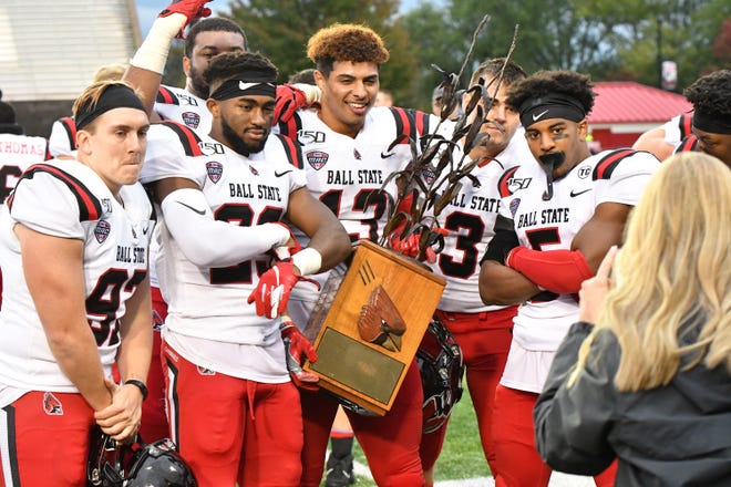 Ball State players celebrate with the Bronze Stalk Trophy after the Cardinals' win against Northern Illinois.