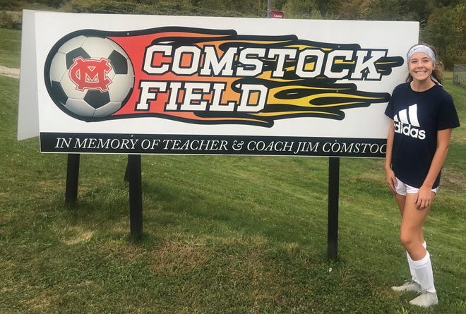 Mansfield Christian's Olivia Bekeleski stands in front of the Comstock Field sign dedicated to her late grandfather, Jim Comstock. She is the only grandchild who plays soccer.