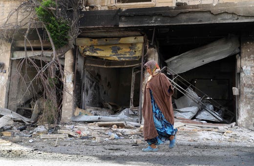 A woman walks on Oct. 6, 2019, past shops damaged in attacks by pro-regime forces in Syria. Despite a ceasefire deal reached on Aug 31, the Idlib province has continued to be targeted by air attacks.