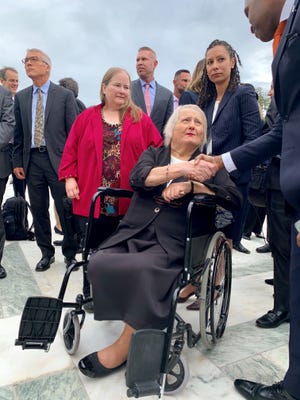 Michigan’s Aimee Stephens, flanked by wife Donna at left and ACLU attorney Ria Tabacco Mar, greets well-wishers outside the U.S. Supreme Court on Tuesday after the justices heard arguments in her case. Rally-goers outside the court chanted her name as she left the building.