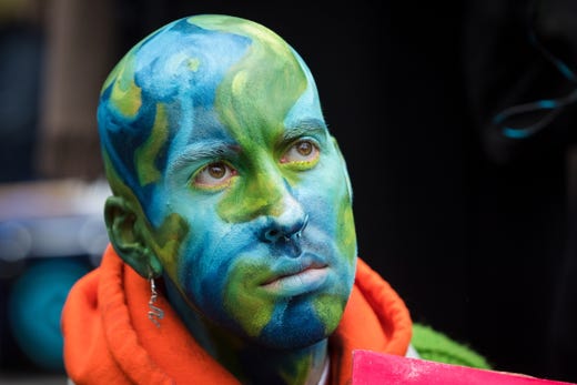 An Extinction Rebellion protester with his head painted in the colors of planet Earth sits in the road in Trafalgar Square during a rally in London on Oct. 7, 2019.