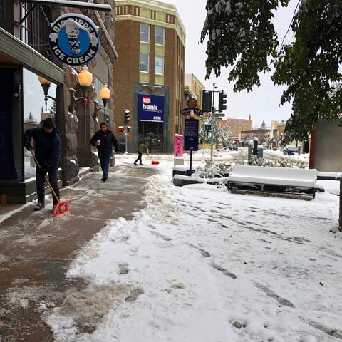People clear the sidewalk after a fall snowstorm i