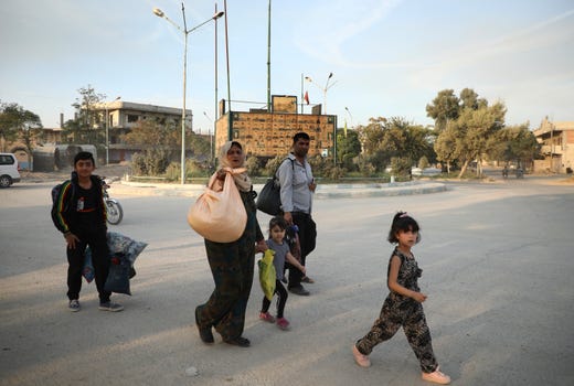 In this photo provided by Rojava Media Center, a pro-Kurdish media group, Syrians carry their belongings, as they flee Ras al Ayn, in northeast Syria, Wednesday, Oct. 9, 2019. (Rojava Media Center via AP) ORG XMIT: XHM103
