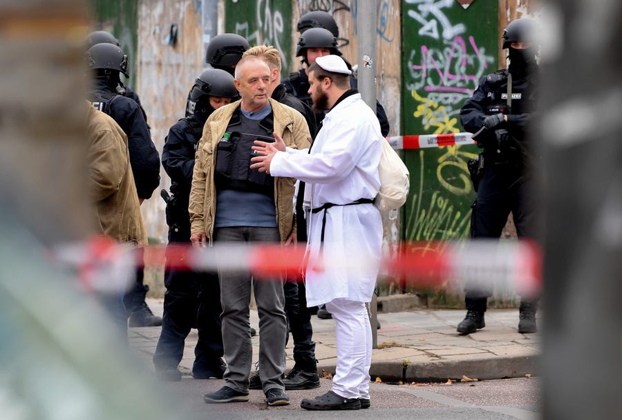 A synagogue visitor talks to police after a shooting at a synagogue in Halle, Germany, October 9, 2019. According to the police two people were killed in shootings in front of a Synagogue and a Kebab shop in the Paulus district of Halle in the East German federal state of Saxony-Anhalt. Police stated a suspect is already in arrest. Media report the mayor of Halle speaks of an amok situation.