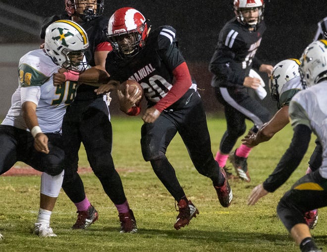Manual running back Deaaron Robinson (20) finds a hole in the St. X line, Friday, Oct. 11, 2019 in Louisville Ky. A cold, rainy game meant lots of yardage on the ground for both teams.