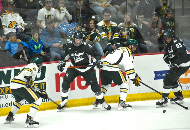 Michigan State's Cole Krygier (8) battles Northern Michigan's Joe Nardi (left) and Darien Craighead along the boards, while MSU teammate Patrick Khodorenko looks on during the second period of Friday night's game in Marquette. MSU won, 5-3.