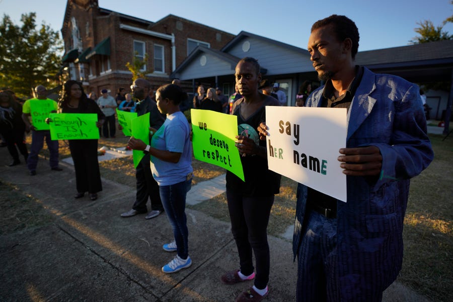 Protesters gather outside the house, right, where Atatiana Jefferson was shot and killed by police, during a community vigil for Jefferson on Oct. 13, 2019, in Fort Worth, Texas. 
