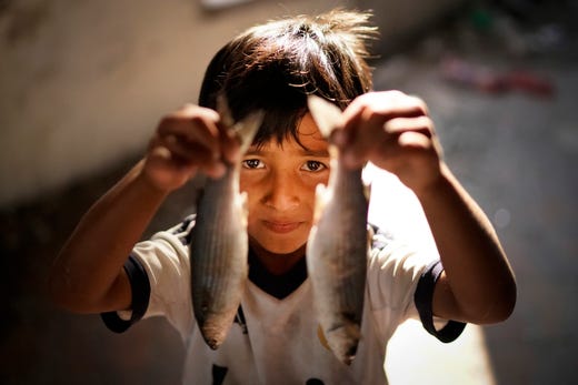 MYTILENE, GREECE - OCTOBER 15: A young migrant boy from Afghanistan, shows off the fish that he and his father have caught for lunch, fishing from a disused warehouse near the Moria Refugee Camp on October 15, 2019 in Mytilene, Greece. Moria migrant camp was built for 3,000 people but is now believed to contain up to 14,000 and has sprawled into the neighbouring olive groves. Migrants have dubbed the new camp 'The Jungle". Authorities have begun to relocate refugees and migrates from overcrowded island hotspots to facilities on the mainland in a bid to ease pressure on the island camps, as the flow of new arrivals from neighbouring Turkey continues. (Photo by Christopher Furlong/Getty Images) ORG XMIT: 775419008 ORIG FILE ID: 1181258554